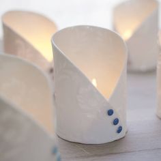 several white cups with blue dots on them sitting on a table next to some candles