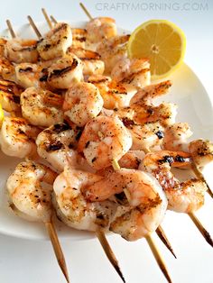 shrimp skewers with lemon wedges on a white plate, ready to be eaten