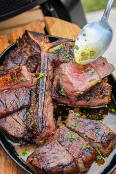 a person is spooning some food out of a skillet on top of steak