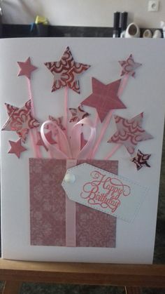 a birthday card with pink and red stars in a gift box that says happy birthday