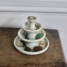 three tiered white ceramic jewelry holder on wooden table