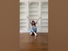 a woman sitting on the floor with her arms in the air