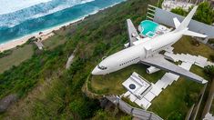 an airplane is parked on the grass by the water and beach in front of it