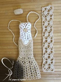 a crocheted dress and hat are sitting on a wooden floor next to a lace doily