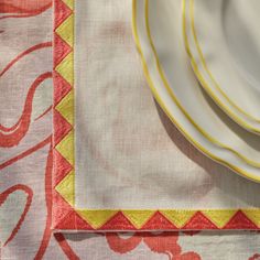 the table cloth has yellow and red designs on it, along with two white plates