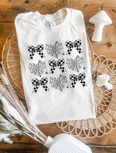 Unleash your child's playful side with our Webs and Bows Coquette Tee! This enchanting t-shirt features a delightful design of charming spiders, heart-shaped spider webs, and black and white checkered bows, all brought to life with vibrant Direct-to-Film (DTF) printing. Made from the soft and durable Bella Canvas 3001Y, this tee ensures comfort and style for your little one. Available in sizes small, medium, large, and extra-large, it's perfect for kids who love a mix of spooky and sweet! Key Features: Material: Bella Canvas 3001Y for a soft, comfortable fit Design: DTF printed spiders, heart-shaped spider webs, and checkered bows Sizes: Small, Medium, Large, Extra Large Color Options: Choose from a variety of fun colors to match your child's personality Perfect For: Everyday wear, Hallowe White Butterfly Print Graphic Tee, Butterfly Graphic Tee, Valentine's Day Heart Print Graphic Tee, Toddler Girl Western Shirts, Bows Coquette, White Cotton T-shirt With Butterfly Print, Spider Webs, Dtf Printing, Kids Tops