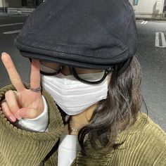 a woman wearing a face mask and making the peace sign with her hand in front of her