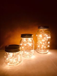 three mason jars with fairy lights in them