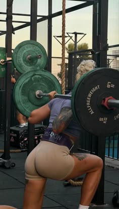 a woman squatting down while holding a barbell