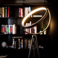 a light that is on top of a tripod in front of a bookshelf