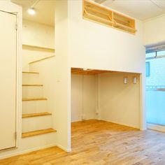 an empty room with wooden floors and stairs in the corner, next to a window