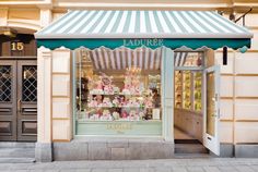 a store front with pink and white cakes in the window