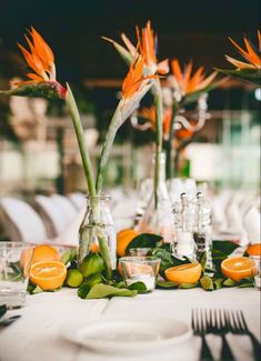 the table is set with oranges and flowers in vases