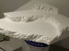 a large white sculpture sitting on top of a table next to a can of paint