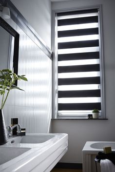 a white sink sitting under a window next to a bath tub