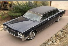 an old black car is parked on the street