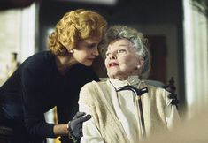 an older woman sitting in a chair next to a younger woman who is looking at her