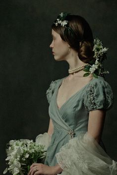 a woman in a green dress with flowers in her hair, holding a white bouquet