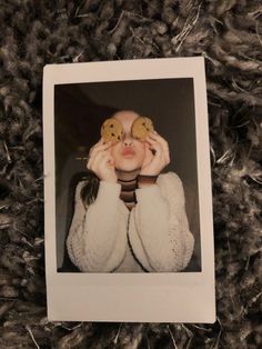 a woman holding two doughnuts over her eyes