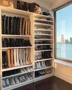 a closet filled with lots of shoes next to a large window overlooking the city skyline