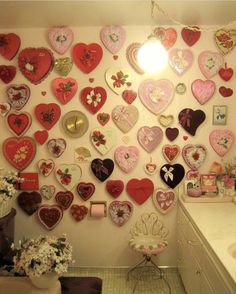 a bathroom with lots of heart shaped magnets on the wall and a sink in front of it