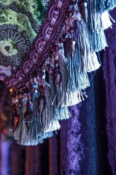 some tassels are hanging on a purple curtain