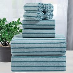 towels stacked on top of each other in front of a potted plant