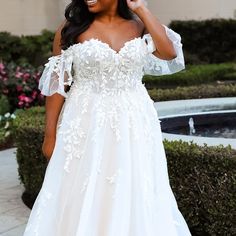 a woman in a white wedding dress posing for the camera with her hand on her hip