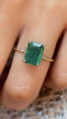 a woman's hand wearing a ring with an emerald and diamond band on it