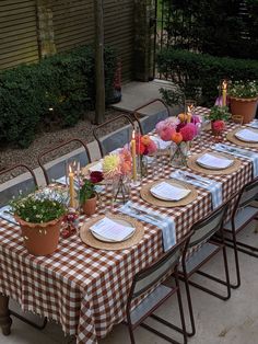 a table set with place settings and flowers in vases on the tables outside at night