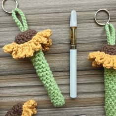 two crocheted items are sitting next to a pen and keychain on a wooden table