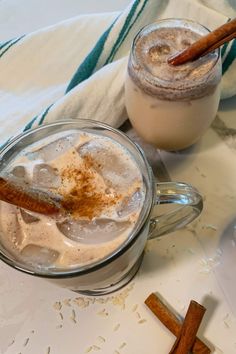 two mugs filled with hot chocolate and cinnamon sitting on a table next to each other