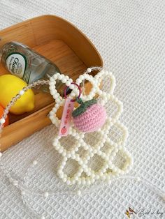 a wooden box with beads and fruit in it sitting on a table next to a bottle