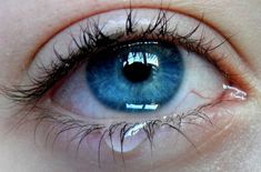 an eye with blue eyes is shown in this close up photo, it appears to be looking at the camera