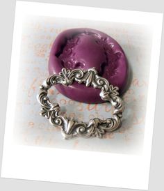 a purple ring sitting on top of a piece of paper with filigrees