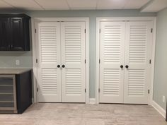 an empty room with two white doors and black cupboards on the wall next to it