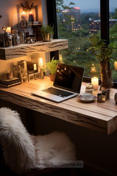 a laptop computer sitting on top of a wooden desk next to a plant and candle