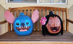 two painted pumpkins sitting on top of a wooden bench