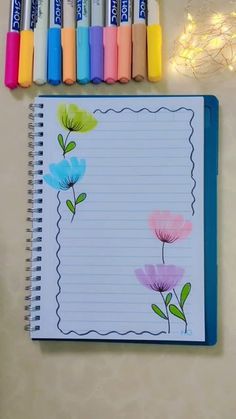 an open notebook with markers and crayons next to it