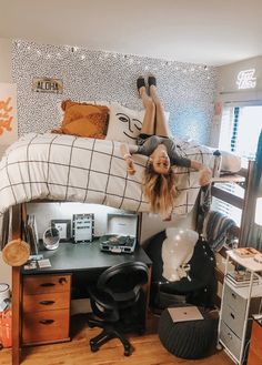 a woman laying on top of a bed next to a desk with a laptop computer