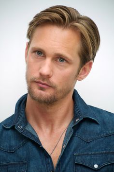 a close up of a person wearing a blue shirt and looking at the camera with a serious look on his face