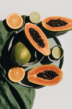 sliced papaya and limes on a plate with a green cloth next to them