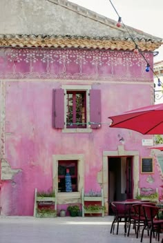 a pink building with tables and umbrellas outside