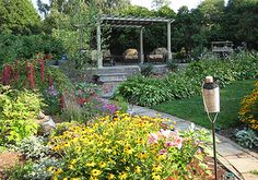 a garden with lots of flowers and plants in the foreground is a gazebo