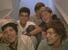 four young men are posing for the camera in front of some stairs with their arms around each other