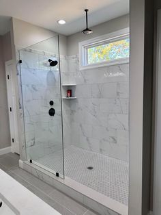 a bathroom with a walk in shower next to a white sink and toilet under a window