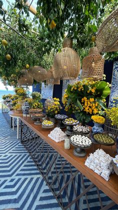 an outdoor buffet is set up with flowers and desserts