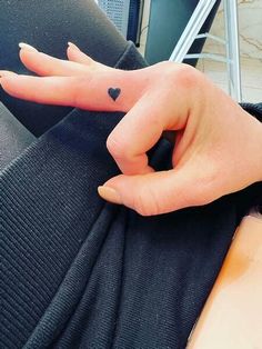 a person with a heart shaped tattoo on their left hand and the other hand is pointing at something