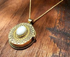 Absolutely beautiful round gold locket pendant with intricate details and a genuine moonstone cabochon!The piece measures 2 inches from the top of the bail to the bottom of the pendant, but the actual locket measures about 1.5 inches.Collected along out journey through Rajasthan India, this piece was made by traditional skilled Indian jewelers. Made with jewelry brass and genuine Moonstone cabochon. Moonstone has long been revered as a guide to our own inner truths. As light catches the stone an Hidden Colors, Gold Locket Necklace, Bohemian Style Jewelry, Locket Pendant Necklace, Gold Locket, Rajasthan India, Moonstone Jewelry, Affordable Gifts, Gemstone Bracelets