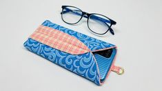 an eyeglass case and pair of glasses on a white surface with a blue background